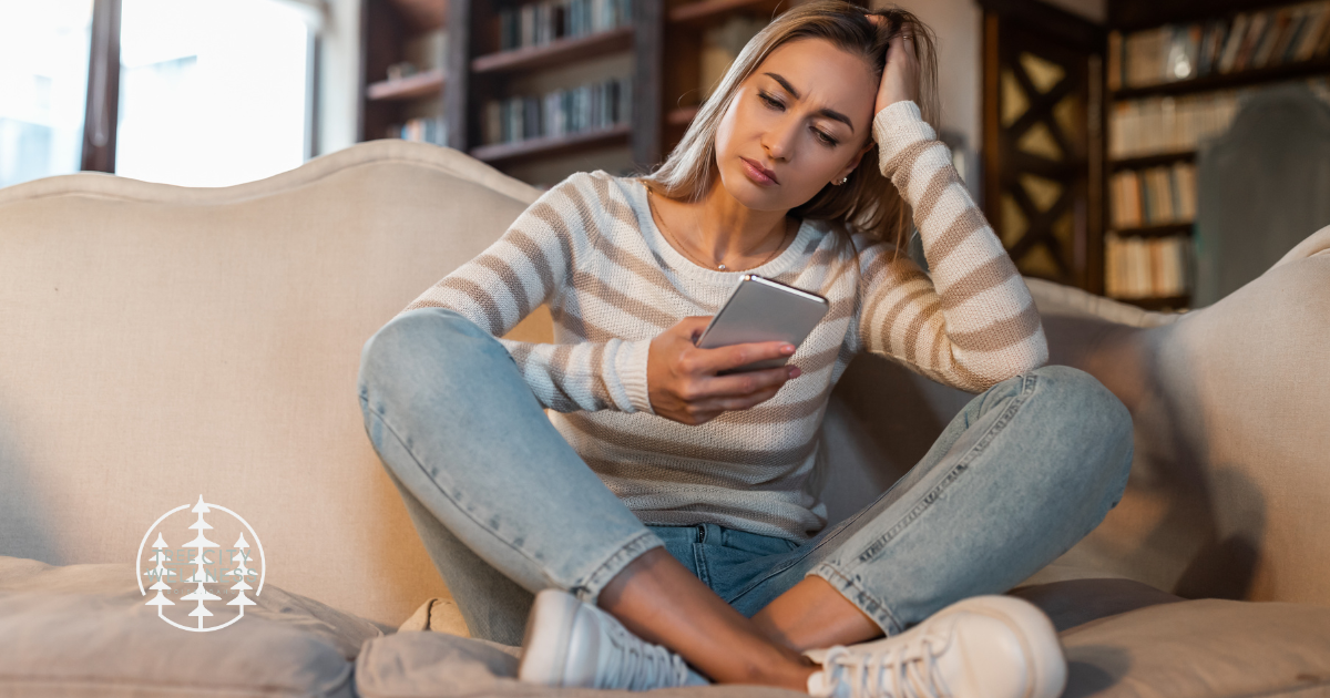 Woman looking at her cell phone looking anxious and distressed. Heading image for blog post about codependency in relationships from tree city wellness